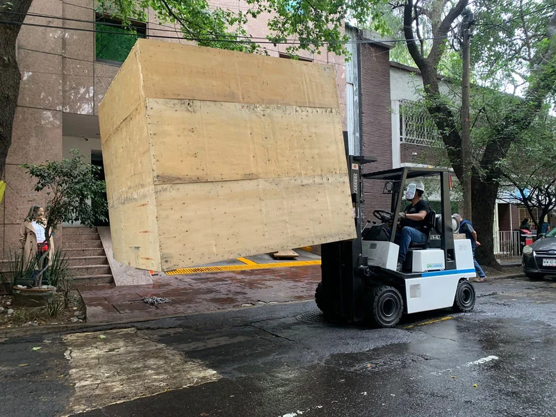 Montacargas industrial de carga pesada trasladando contenedor de maquinaria en maniobra urbana
