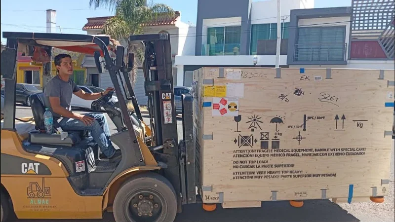 Montacargas CAT transportando contenedor de equipo industrial en zona de carga
